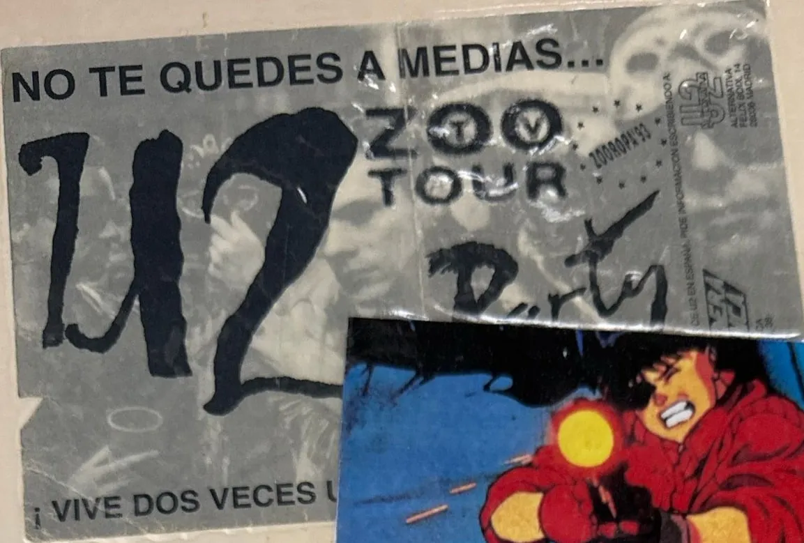 Entrada gris de una fiesta del U2 Zoo TV Tour, con «Party» escrito a mano, tapada en parte por un fotograma de Kaneda, de Akira.